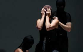 A promotional photo for the dance performance featuring the three dancers wearing balaclavas covering their face.