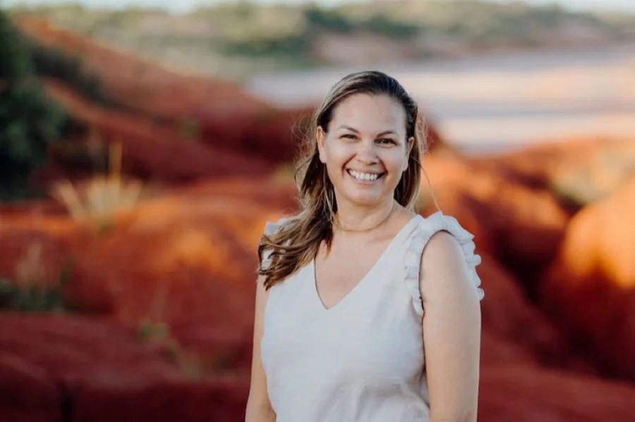 Naomi Pigram-Mitchell is Black Swan State Theatre Company's new Associate Artistic Director. A smiling Aboriginal woman in a sleeveless dress smiles at the camera.