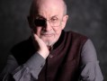 elderly man dressed in dark colors looking serious with one eye patch. Salman Rushdie