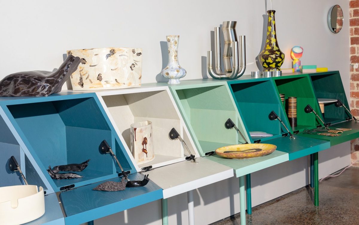 An installation of opened cabinets varying from green to white and blue, with design objects including glass slugs, ceramics and jars. Opportunities and call-outs.