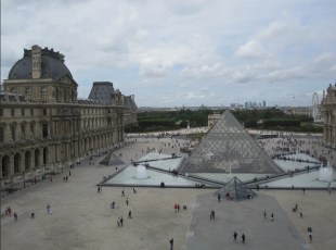 Exterior view of historical building and forecourt with people. The Louvre