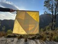 Close up photograph of a person's arm holding a yellow signal flag in the landscape as part of The Unconformity.