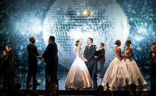 Sydney’s Pinchgut Opera is the first Australian company to utilise Spektrix’s integrated, intuitive CRM platform. Pictured is Pinchgut’s recent production, ‘The Fairy Queen’. A cast in suits and white ball gowns sing, embrace and hold hands on a mirrored stage; a giant mirrorball is projected behind them.