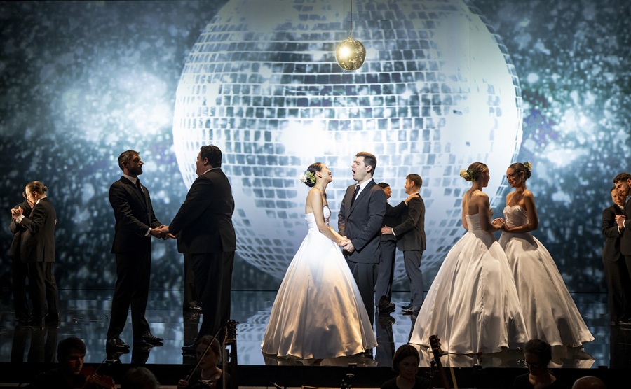 Sydney’s Pinchgut Opera is the first Australian company to utilise Spektrix’s integrated, intuitive CRM platform. Pictured is Pinchgut’s recent production, ‘The Fairy Queen’. A cast in suits and white ball gowns sing, embrace and hold hands on a mirrored stage; a giant mirrorball is projected behind them.