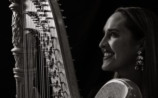 A black and white photo with high contract is a woman with her side profile holding a harp.