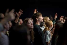 access and inclusion: a photo of a group of young people in the their late teens and early twenties standing in a crowd watching a music concert against a black background.