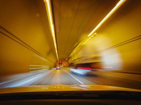 An underground stretch of road in a tunnel. The yellow-tinged photograph shows vehicles moving through the tunnel at speed, with details blurred to suggest their rapid movement. The photo illustrates Artshub's On the Move column of arts industry appointments.