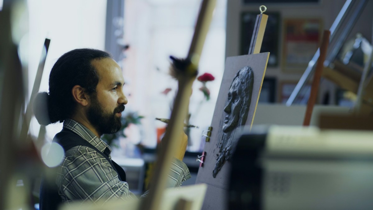 A sculpture working on a relief in a studio environment. Basic income in Ireland can support artists. 