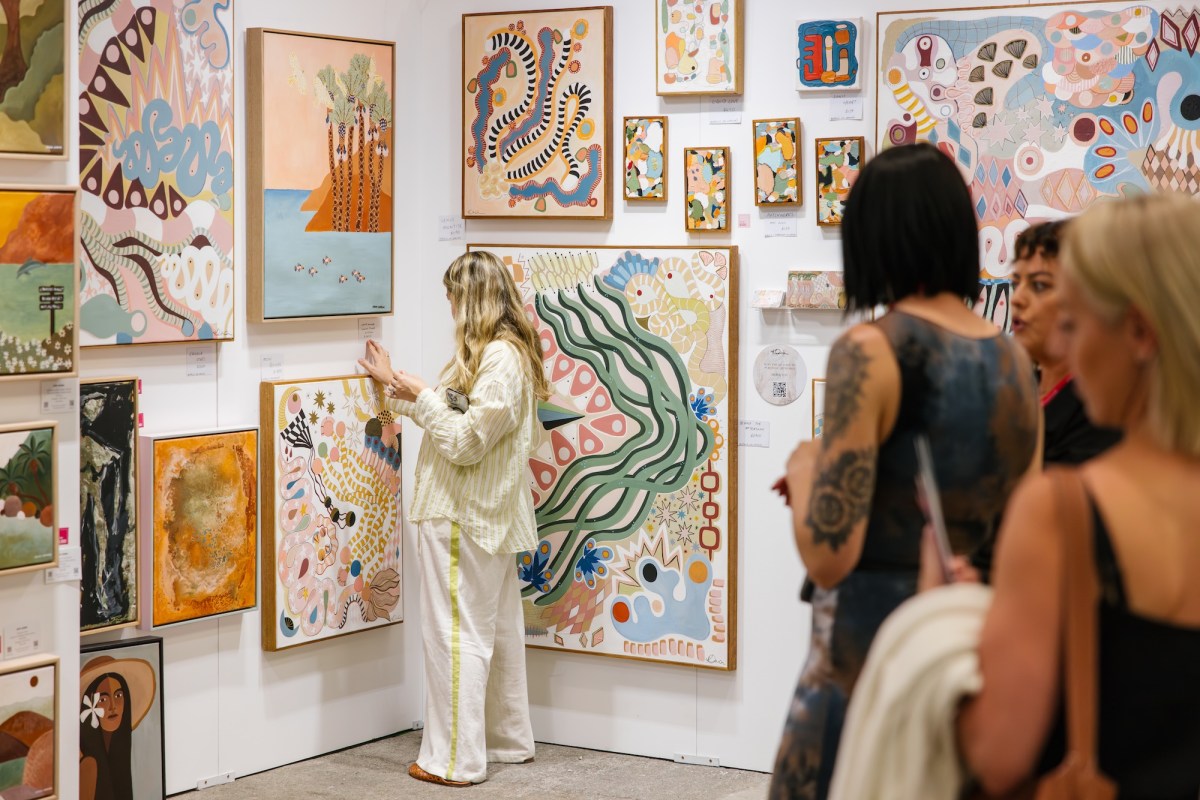 Blonde hair girl looking at paintings in an art fair setting.