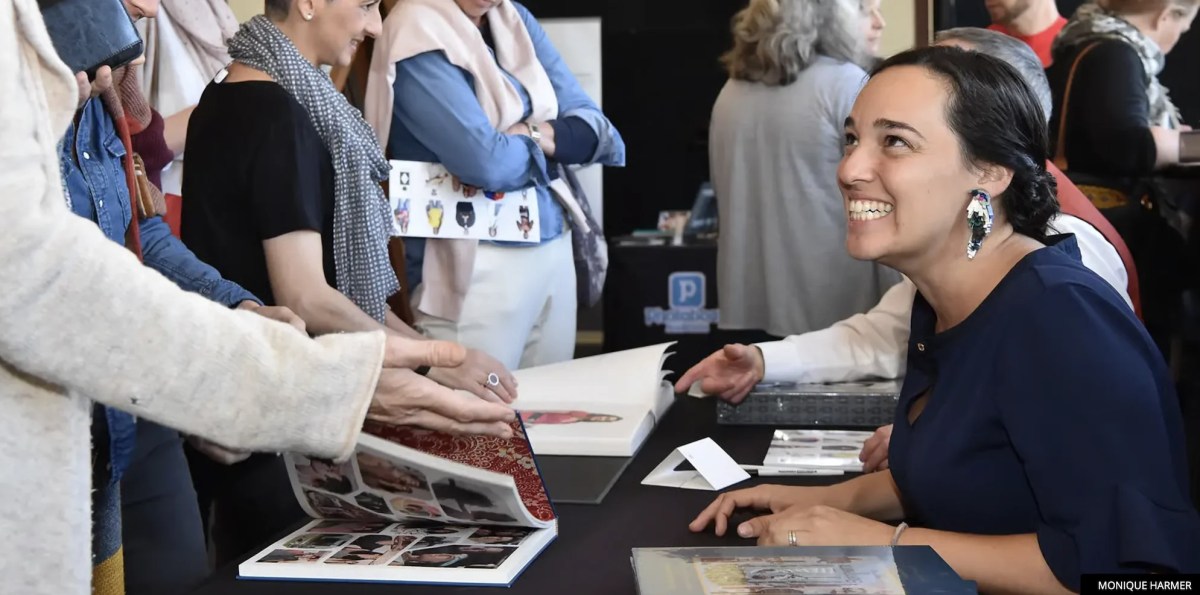 Woman at market / fair with books open. Head On Photo Festival