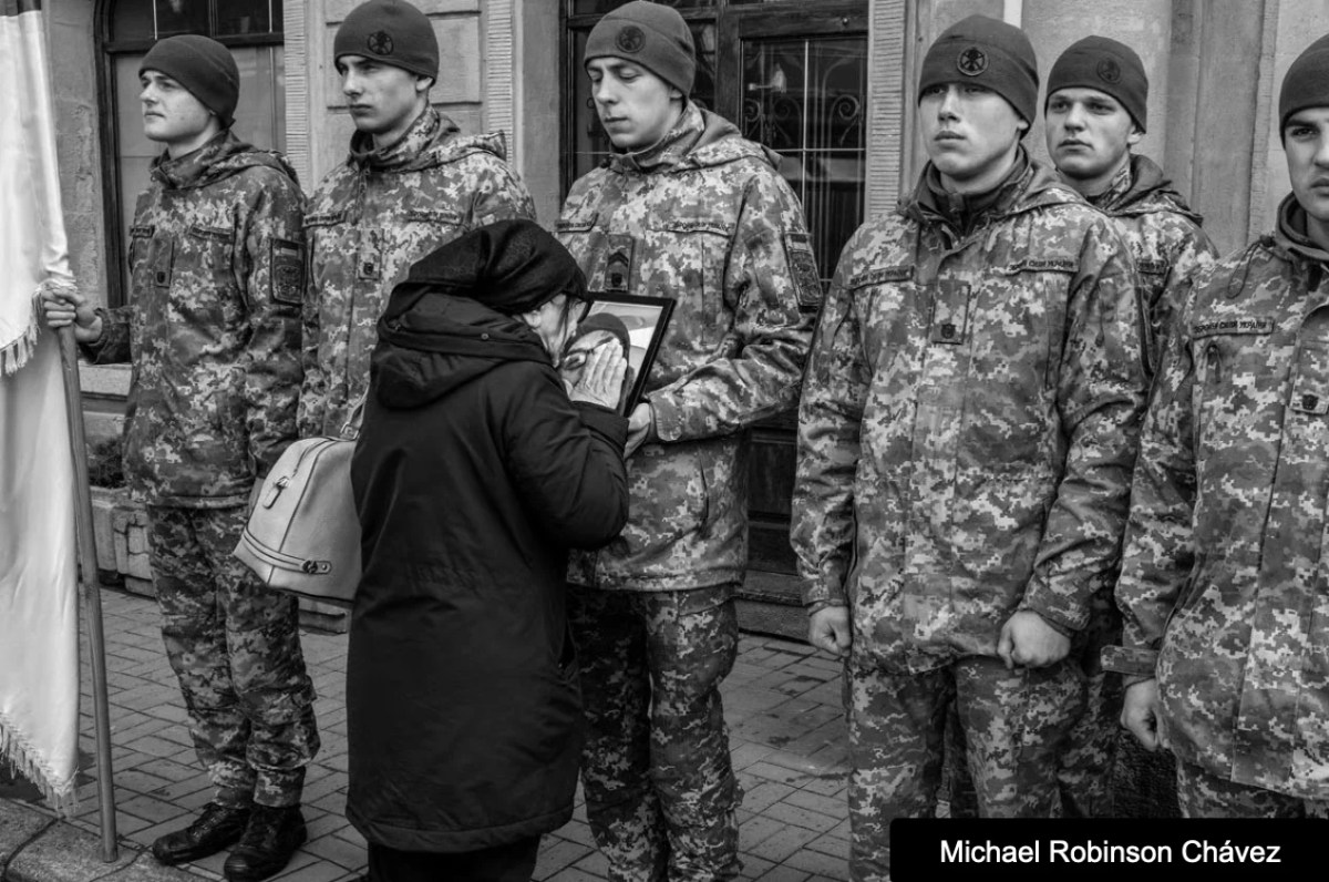 Soldiers in uniform with a women dressed in black looking at image. Head On Photo Festival