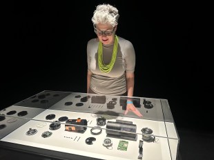 Woman with grey hair looking into museum case with AI technology