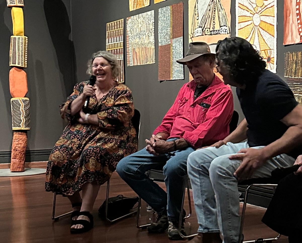 woman with curly hair and patterned dress talking in panel in gallery setting with two male artists. Aboriginal art