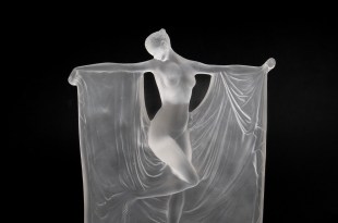 Glass sculpture of woman with outstretched arts and draped fabric in Art Deco style.