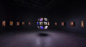 Exhibition gallery view of video work on a floating globe in darkened space. cool exhibitions