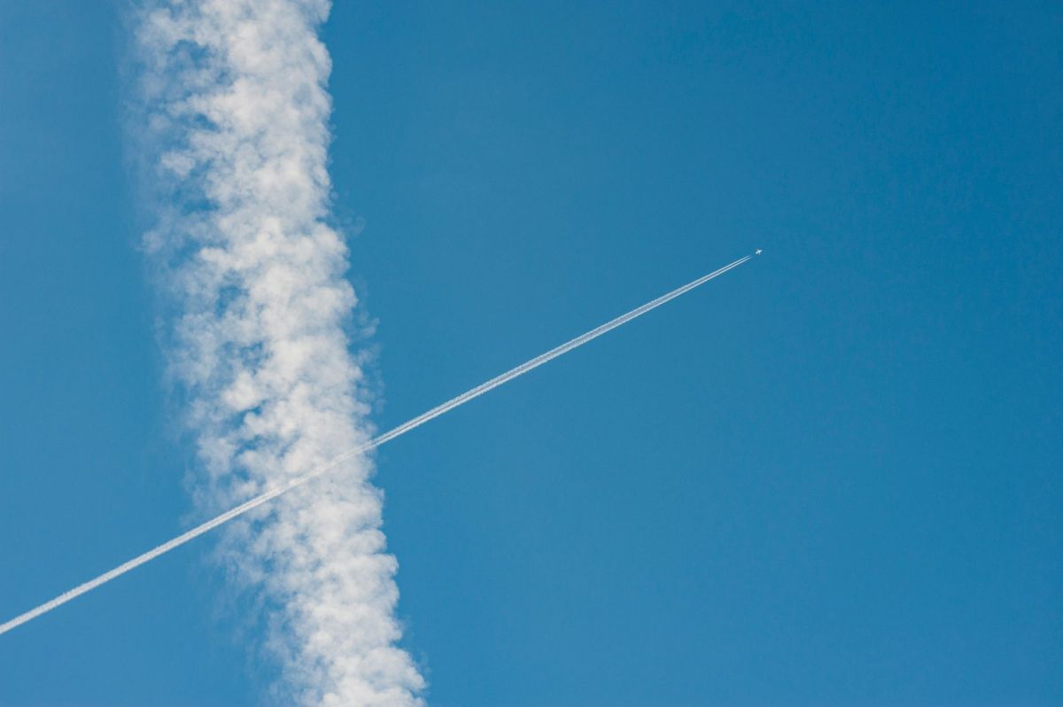 A passenger jet's contrail draws a diagonal line across a blue sky, intersecting with a puffy cloud that runs vertically from the top to the bottom of the frame. arts sector appointments