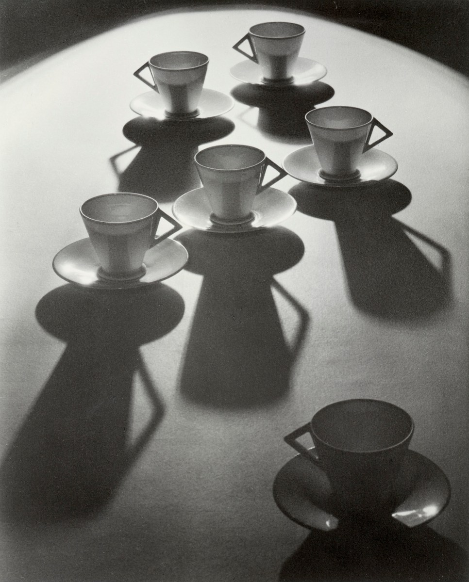 dramatic light black and white photograph of art deco teacups. Women photographers
