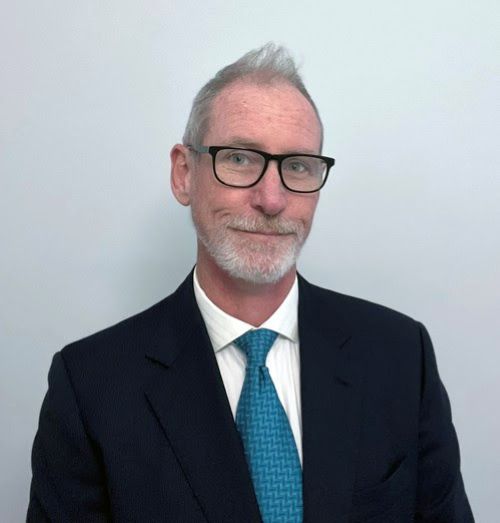 Dr Kent Wilson as the new Director of NETS Victoria. An older, fair-skinned man with thinning grey hair and a closely trimmed white beard and dark glasses.