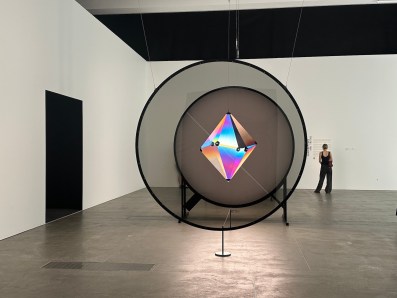 Gallery view with woman in black with centre installation using polarising filters. Olafur Eliasson