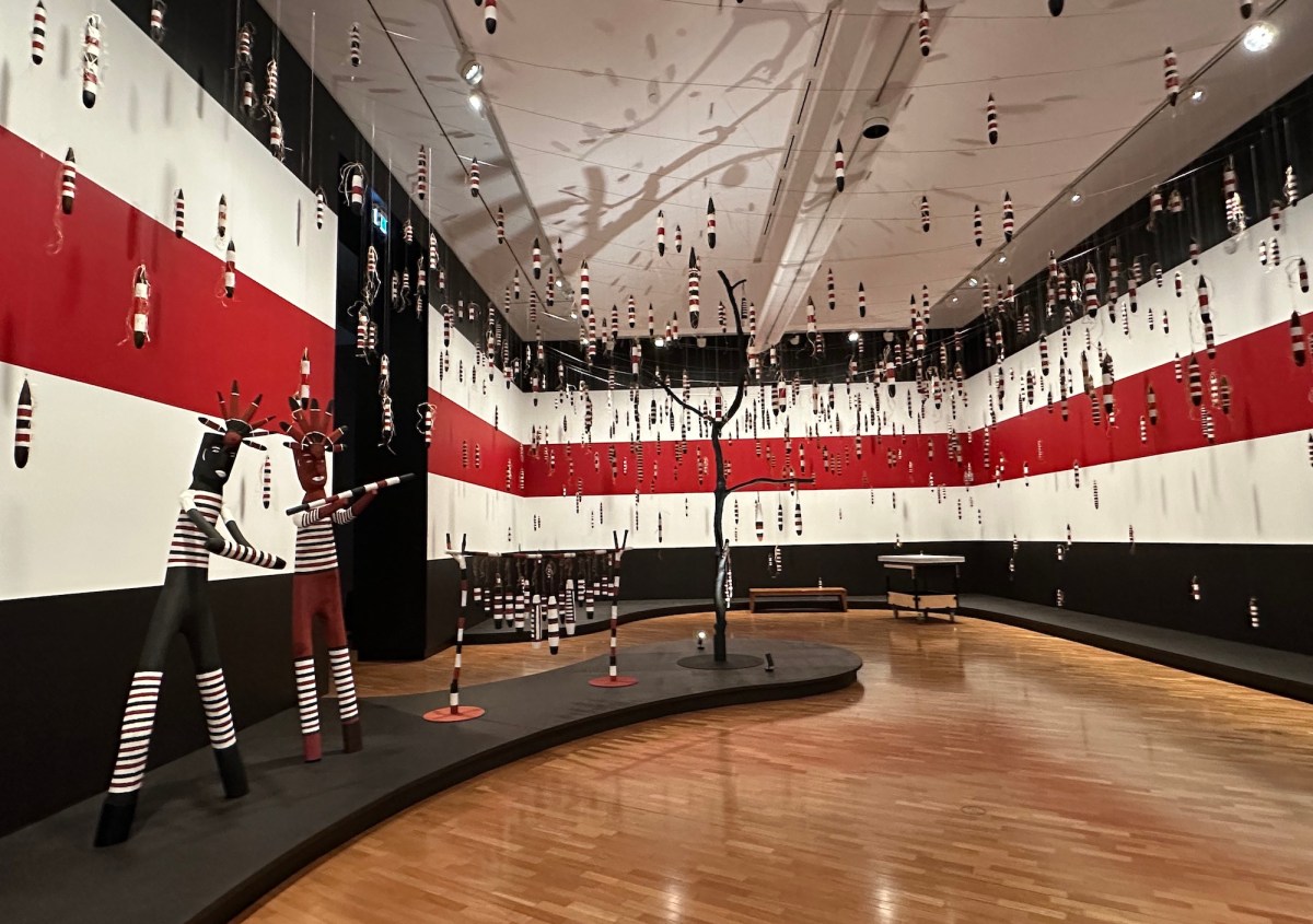 Room with walls painted in red white and black stripes and installation of Aboriginal art sculptures. Tony Albert's Indigenous Triennial