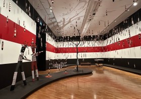 Room with walls painted in red white and black stripes and installation of Aboriginal art sculptures. Tony Albert's Indigenous Triennial