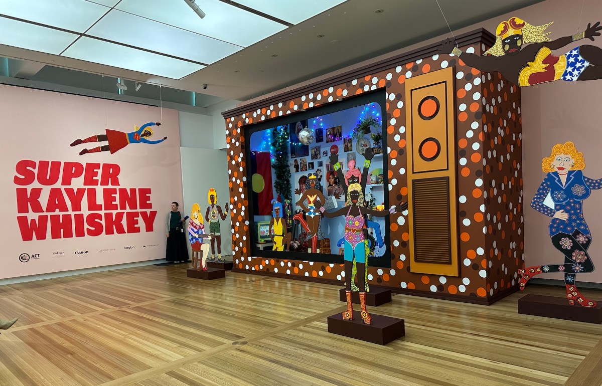 Entrance to an exhibition with an installation and red text. Kaylene Whiskey