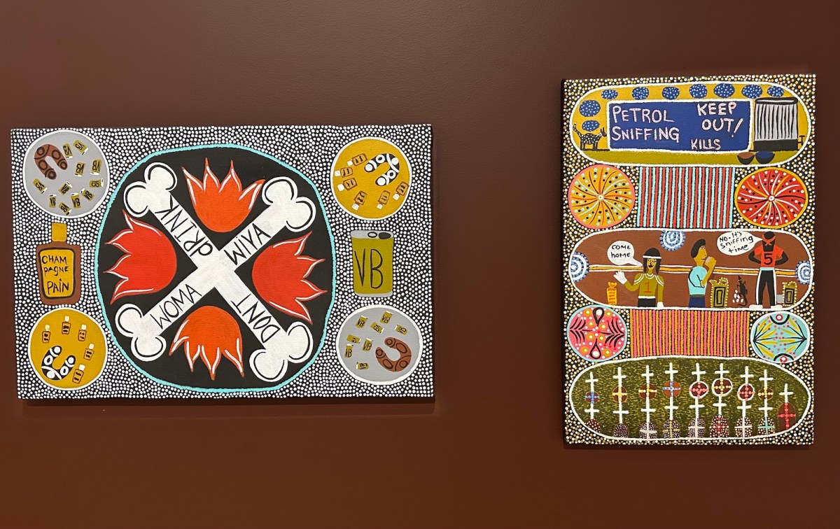 Two Aboriginal paintings with dot art and political message on brown wall. Kaylene Whiskey