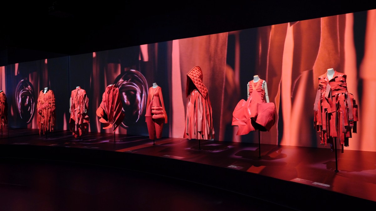 Exhibition of garments in red against a red video projection. Westwood Kawakubo