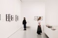 Two women in a gallery setting looking at an historic exhibition of women photographers