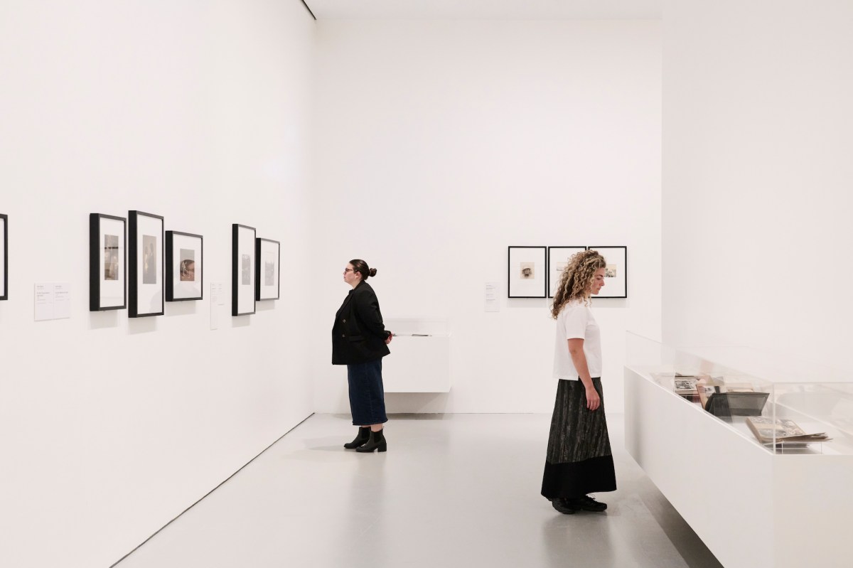 Two women in a gallery setting looking at an historic exhibition of women photographers