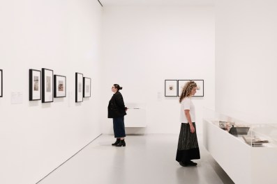 Two women in a gallery setting looking at an historic exhibition of women photographers