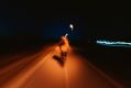 A cyclist photographed from behind on a road at night; the image is blurred, suggesting the photograph was taken by another cyclist while moving. arts sector appoinments
