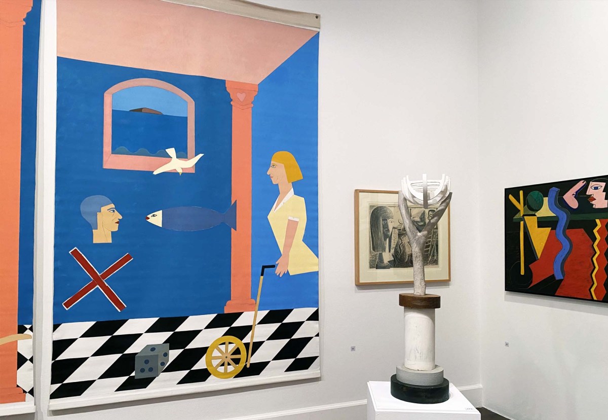 Objet D'art: Theo Koning: a photo of part of a gallery space showing a large brightly coloured canvas painting on one wall next to a freestanding wooden sculpture piece and a smaller coloured painting on the other wall.