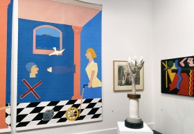 Objet D'art: Theo Koning: a photo of part of a gallery space showing a large brightly coloured canvas painting on one wall next to a freestanding wooden sculpture piece and a smaller coloured painting on the other wall.