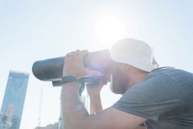 Julia Phillips' Observer, Observed at Sydney Festival 2026. A man ion a white Terry Towling hat peers through a pair of bespoke binoculars, which form part of the artwork.
