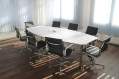 arts board in crisis: a photo of a room with an empty board room table. It's a white oblong table with 8 executive style black chairs around it.