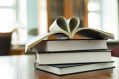 Four books in a pile; the topmost book is open, with two pages bent together to form the shape of a love heart. Indie Book Awards 2026, indie book awards