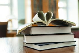 Four books in a pile; the topmost book is open, with two pages bent together to form the shape of a love heart. Indie Book Awards 2026, indie book awards
