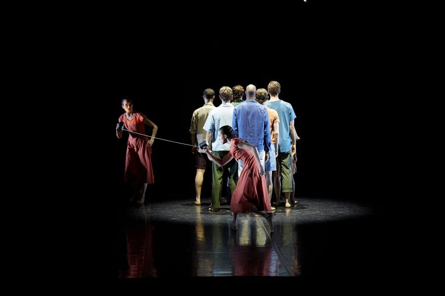 Alexa Tuzil and Nikki Blain with the dancers of West Australian Ballet in Tim Harbour’s Once and Future for Ballet at the Quarry: Incandescence, 2026. Tuzil  and Banks are identically dressed in red dresses and are connected by a cord held in their right hands. They corral a group of six male dancers, all with their backs to the camera.