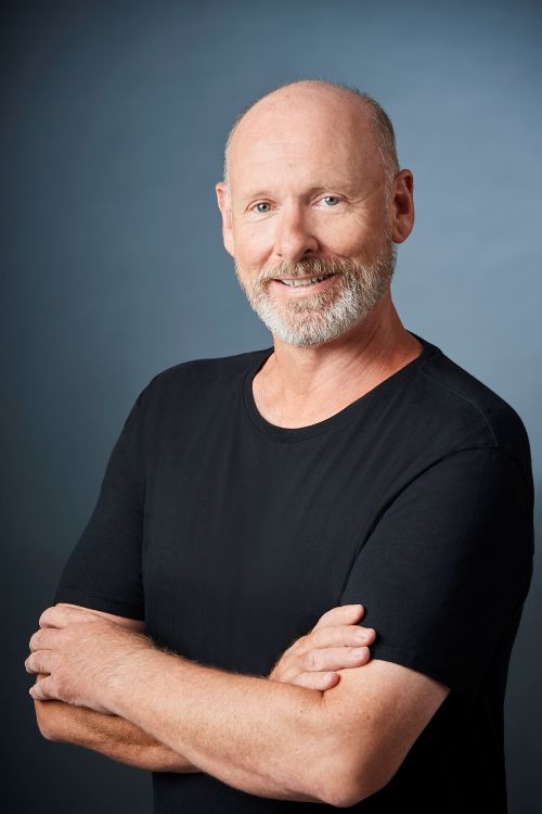 Greg Horsman is the West Australian Ballet's new Rehearsal Director. Greg smiles at the camera with his arms crossed. He wears a black thsirt, has fair skin, a short, neatly trimmed grey beard and short grey hair, though he is partially bald. arts sector appointments