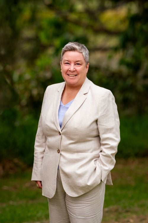 Barking Gecko Arts ambassador Jodi Cant, a middle-ag, fair skinned woman with short grey hair and wearing a white suit.