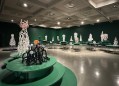 view of gallery exhibition of fantasy like ceramics in a room painted dark green. Lynda Draper