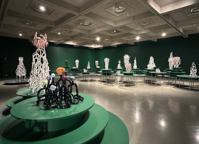 view of gallery exhibition of fantasy like ceramics in a room painted dark green. Lynda Draper