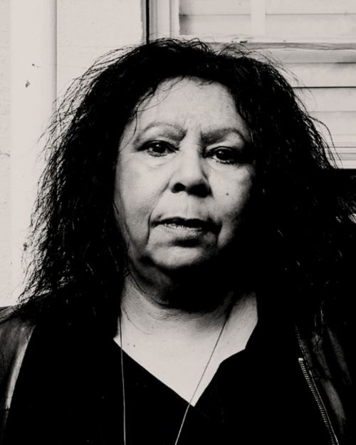 Maree Clarke joins the ACCA Board.  The black & white photo is of a middle-aged Aboriginal woman with long dark hair; she looks direcly into the camera.