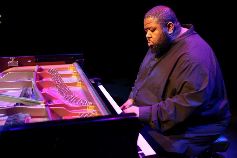 Tyshawn Sorey: Alone at Adelaide Festival 2026. A large, African American man with closely cropped black hair anda matching beard, plays at anopen-topped piano.