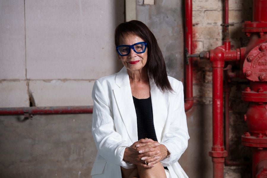 Rhoda Robrta AO, an Aboriginal woman with long black hair and black-framed glasses.  She sits with her legs crossed, her hands clasped over her knees and wears a hite jacket over a black t-shirt.