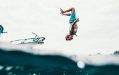 A fair skinned man wearing blue shorts does a backflip of a boat into the water. arts sector appointments
