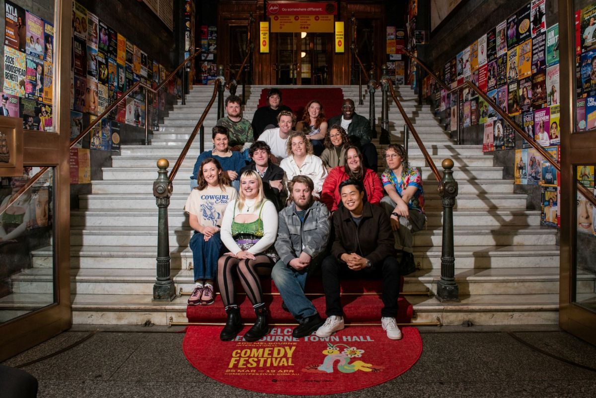 The 2026 Melbourne International Comedy Festival Award nominees, a large and diverse group of people, seated on the steps of Melbourne Town Hall. MICF Award nominees