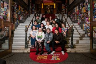 The 2026 Melbourne International Comedy Festival Award nominees, a large and diverse group of people, seated on the steps of Melbourne Town Hall. MICF Award nominees