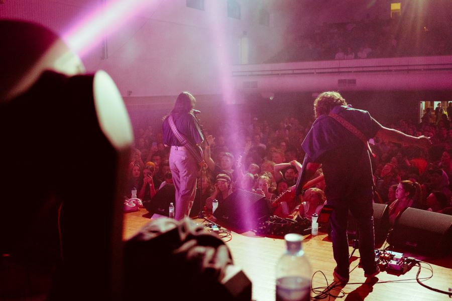Young people at a gig organised by The Push. The photo is taken from the side of the stage, and shows two musicians performing to a throng of young people in a small theatre. 10-year plan for young Australians and music
